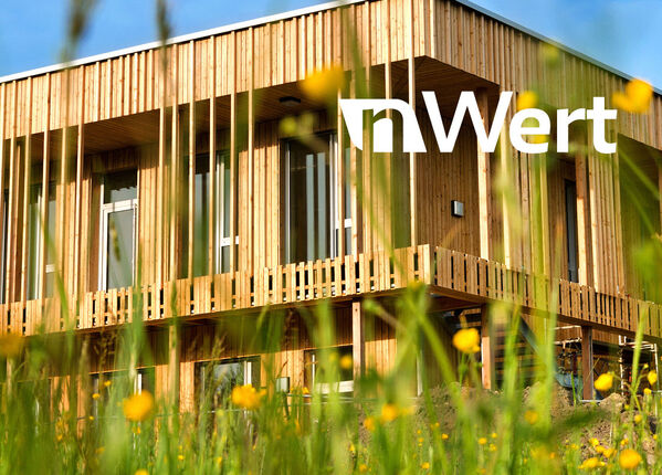 Holzhaus mit blauem Himmel im grünen Gras.
