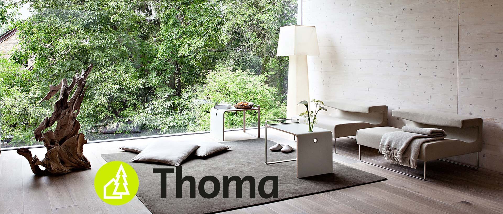 Wohnzimmer mit Blick in einen Garten mit Logo von Thoma