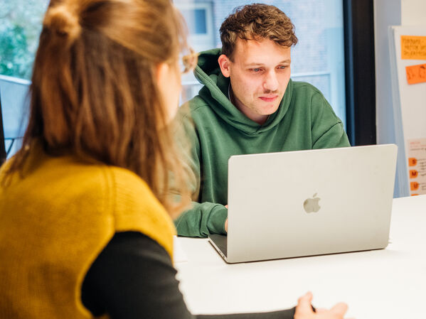Eine junge männlich gelesen Person am Laptop.