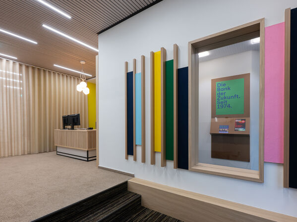 Büro mit bunten Holzelementen an einer hellen Wand,