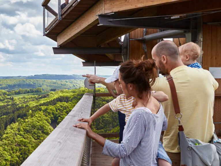 Familie mit Kindern auf einer Aussichtsplattform mit Blick über ein Flusstal