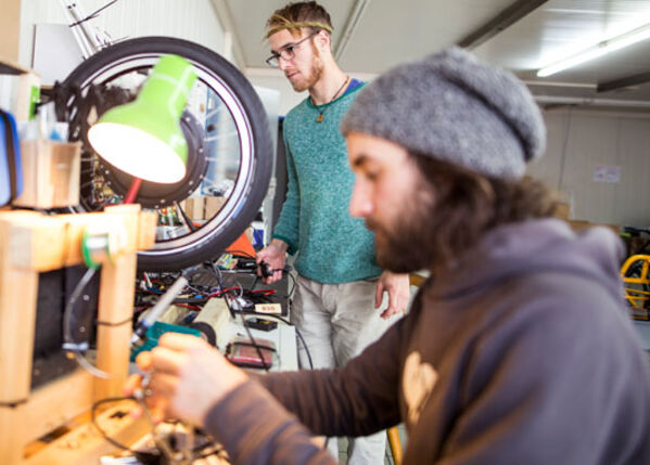 Männlich gelesene Person arbeitet in einer Werkstatt.