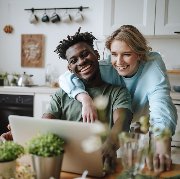 Eine Frau und ein Mann in einer Küche vor einem Laptop