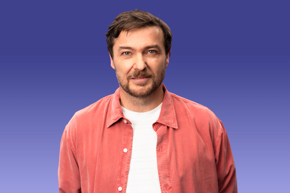 Mit Dir. Mit uns. Für alle. EWS Portraitaufnahme von Sebastian Sladek mit offenem rotem Hemd und weißem T-shirt.