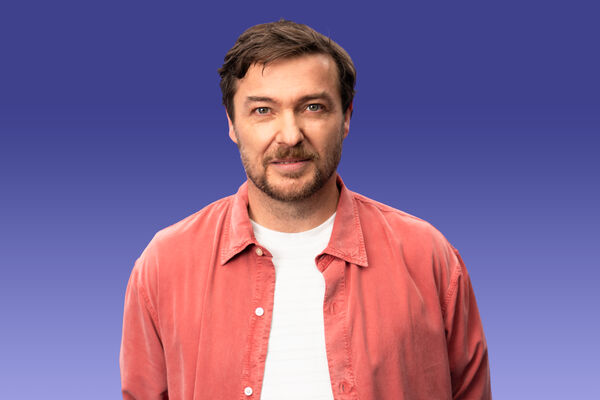 Portraitaufnahme von Sebastian Sladek mit offenem rotem Hemd und weißem T-shirt.