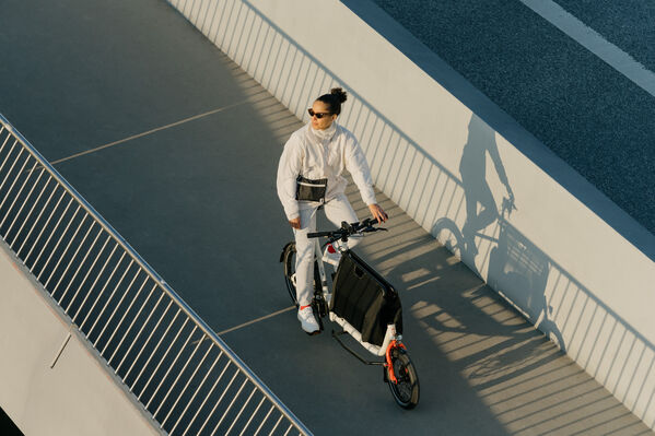 Person ist weiß angezogen und fährt auf einem Lastenrad von Muli-Cycles