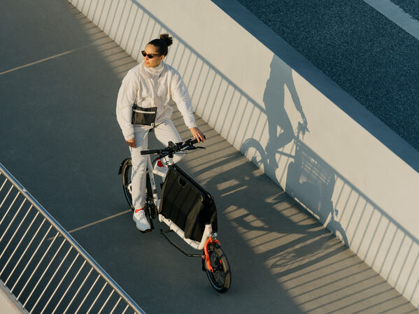 Person ist weiß angezogen und fährt auf einem Lastenrad von Muli-Cycles