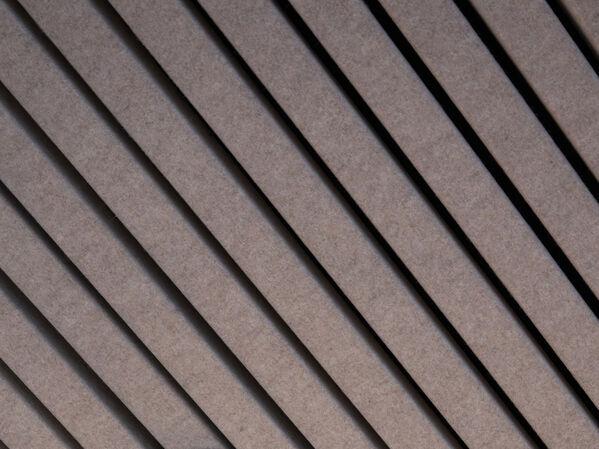 Ein Lampenkabel hängt von einer Decke herab, an der in gleichmäßigen Abständen Holzlatten angebracht sind.