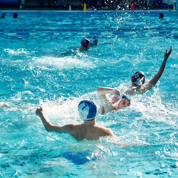 Personen die im Schwimmbad Wasserball spielen.
