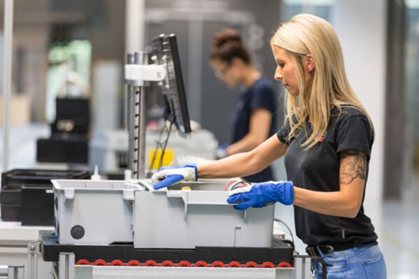 Weiblich gelesene Person mit Arbeitshandschuhen bei der Arbeit.