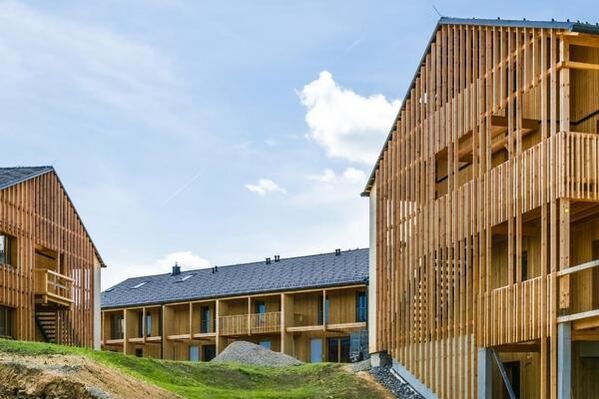 Hölzerne Wohngebäude im Bau mit blauem Himmel und verstreuten Wolken.
