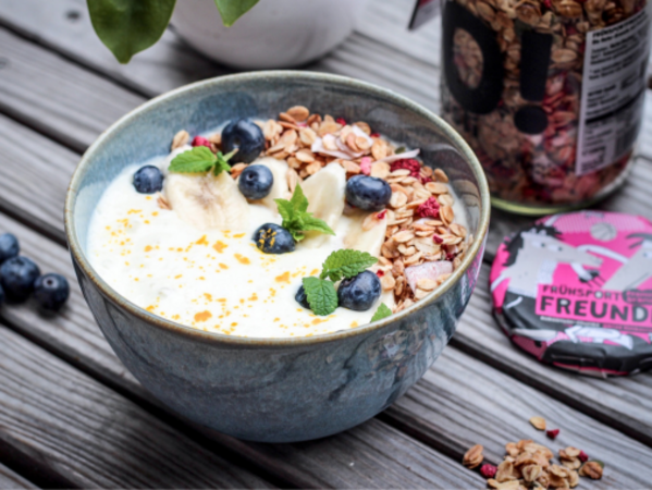 Granola mit Früchten und Joghurt in einer Müslischale.