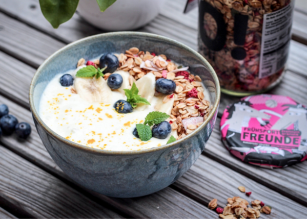 Granola mit Früchten und Joghurt in einer Müslischale.