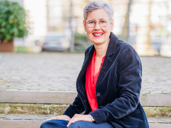 Antje Tönnis lächelnd auf einer Bank sitzend.