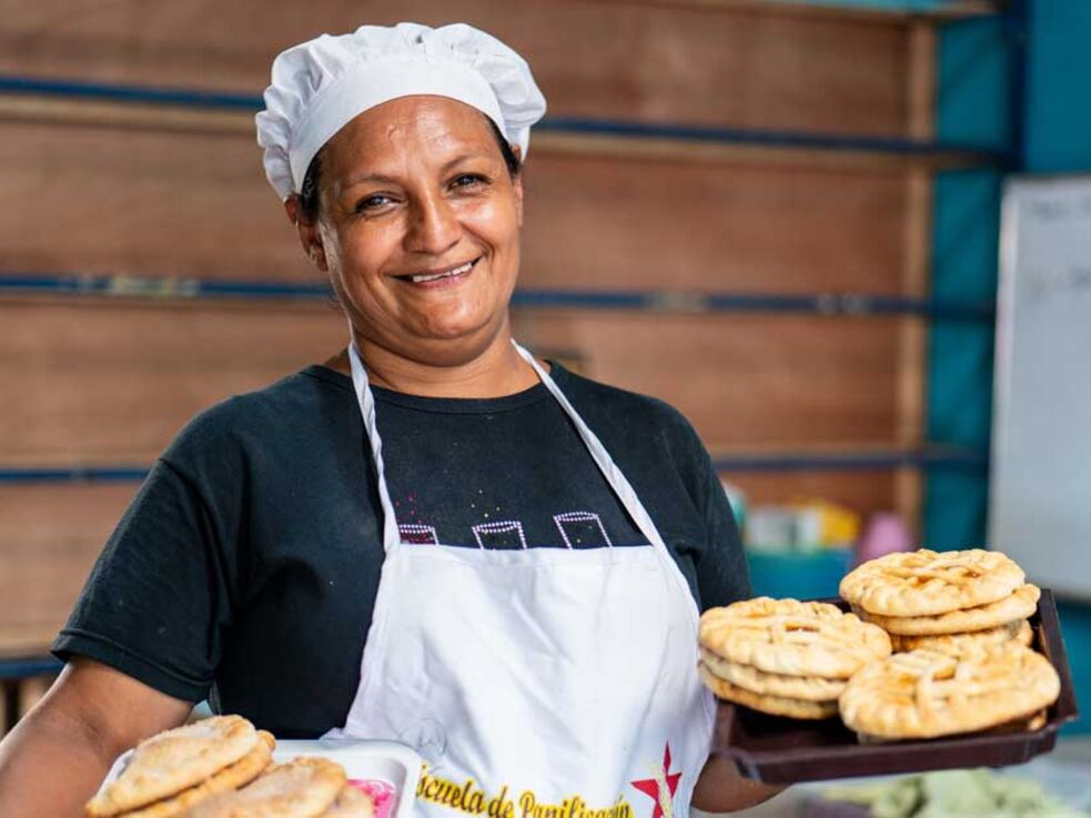 Weiblich gelesen Person mit Backwaren im Verkaufsladen: Pro Mujer - GLS AI - Mikrofinanzfonds