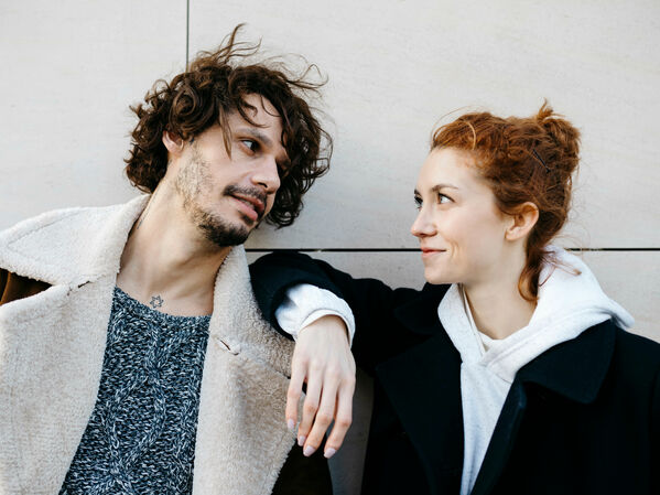 Junger Mann und junge Frau lächeln sich an