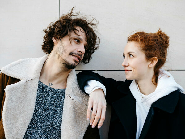 Junger Mann und junge Frau lächeln sich an