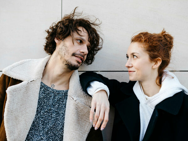 Junger Mann und junge Frau lächeln sich an