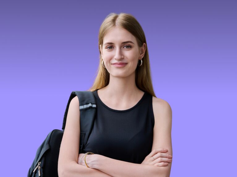 Junge Frau mit langen Haaren, schwarzem Oberteil und Rucksack, verschränkte Arme.