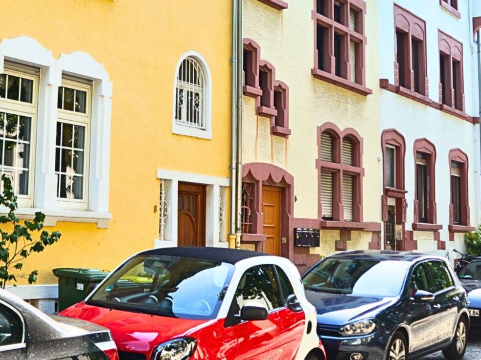 Straße in einer Stadt mit geparkten Autos und Häusern.