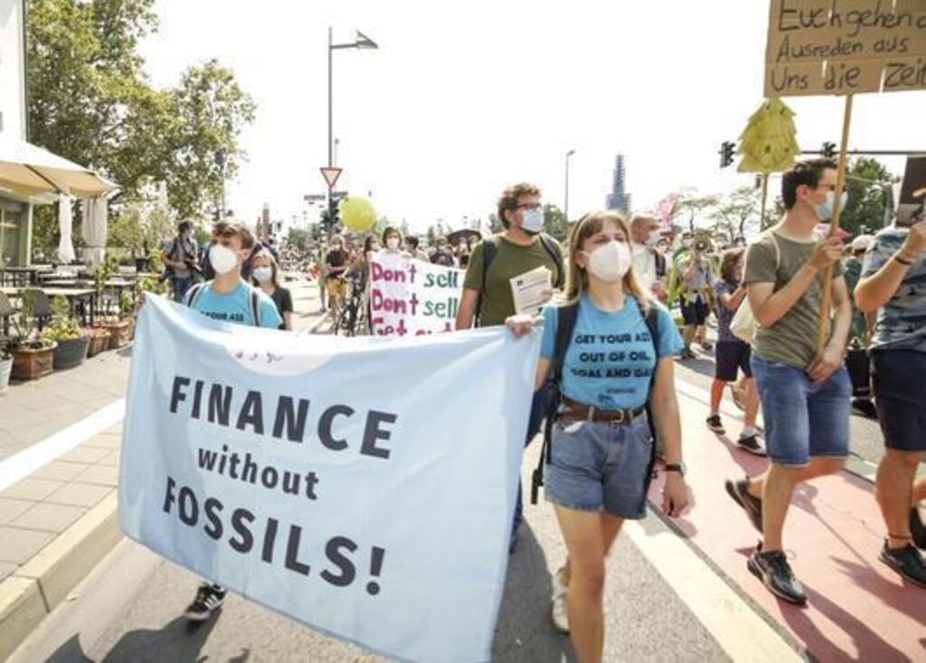 Demonstrant*innen mit Banner "Finance without Fossils" - Ausschnitt aus dem Filmplakat "urgewald - Auf den Spuren des Geldes"